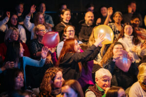 Disrupt Audience catching baloons. The balloons were used during a performance so that Deaf audience members could feel the vibrations of the music through the balloon.