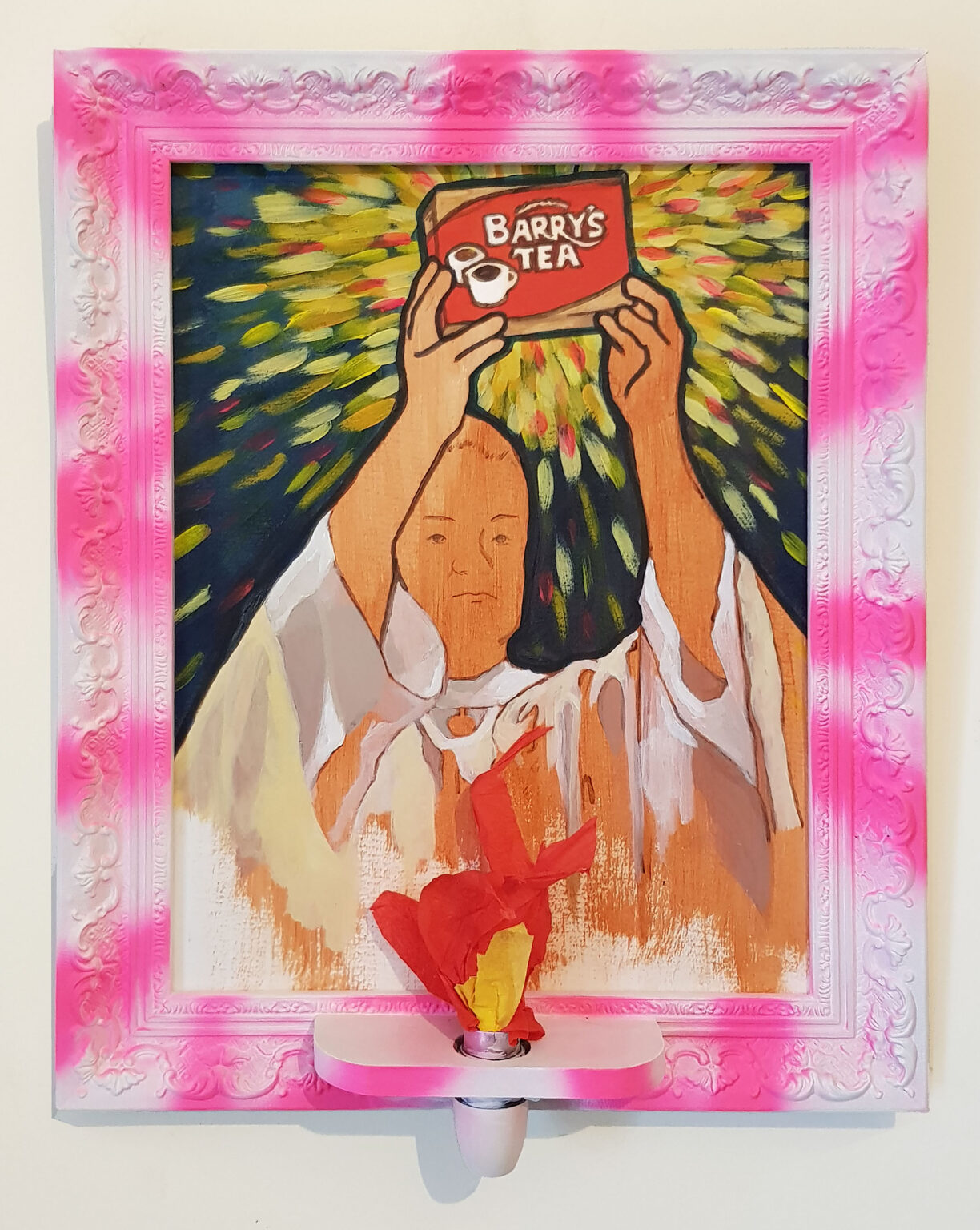 A photograph of a bright, framed painting on a white wall. The central figure appears to be a Catholic priest shown from the chest up, wearing white robes with long wide sleeves. His expression is resolute and calm, his gaze stares out of the frame to the right. His arms are raised high above his balding head, offering up a box of Barry’s Tea painted in its iconic red and gold colours. Behind the tea, dynamic streaks of yellow and red radiate outward against a dark blue background, highlighting the status of the box of tea. The ornate frame is painted white and then spray painted with wavy bright pink lines. Attached to the front of the frame is a vibrant red and yellow flame made of crepe paper, like a votive candle.